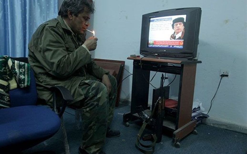 Лівійська Арабська Джамахірія, Аждабія. Лівійський повстанець курить під час перегляду новин про лівійського лідера Муаммара Каддафі. Урядові війська продовжують наступ на повстанців і відвойовують у них ключові міста. / © AFP