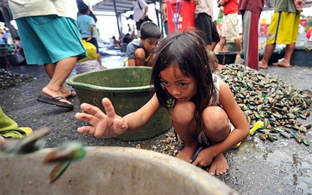 Філіппіни, Маніла. Дівчинка чистить мідії на рибному ринку у передмісті Маніли. / © AFP