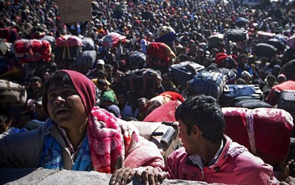 Туніс. Людина намагається перелізти через стіну, щоб уникнути тисняви у багатотисячному натовпі біженців, які намагаються перетнути кордон між Лівією та Тунісом у прикордонному пункті Рас Єдір. / © AFP