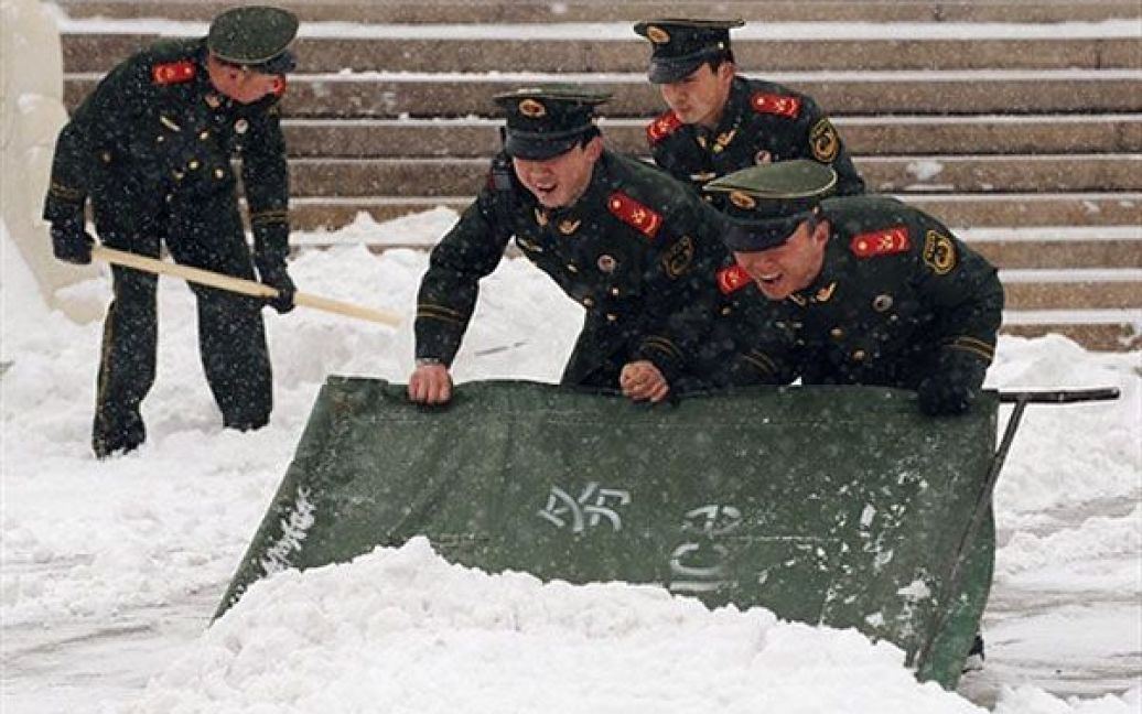 Китай, Пекін. Китайські поліцейські прибирають сніг на площі Тяньаньмень у Пекіні. Снігопад у Пекіні став першими опадами в цьому регіоні з моменту дощу, який випав у столиці 25 листопада минулого року. Очікування першого снігу в Пекіні стало найдовшим за останні 60 років. / © AFP