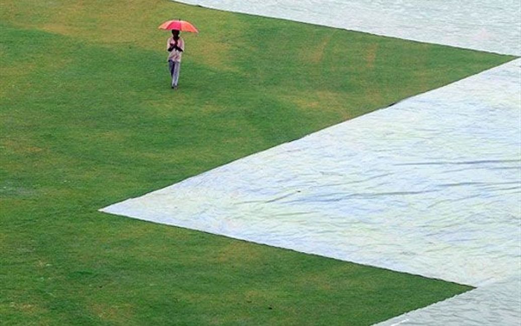 Шрі-Ланка, Сурьявева. Чоловік тримає над головою парасольку, доки він йде полем стадіону для гри у крікет. / © AFP