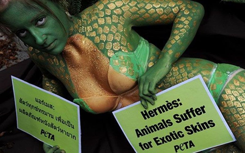 Таїланд, Бангкок. Активістка організації "Люди за етичне поводження з тваринами" (PETA), тіло якої розфарбоване "під зміїну шкіру", позує під час акції протесту біля входу до одного з торгових центрів у Бангкоку. Акція протесту була організована, щоб засудити використання шкур екзотичних тварин для виготовлення розкішного одягу. / © AFP