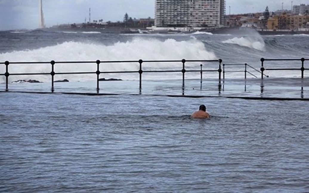 Іспанія, Тенеріфе. Людина плаває у воді, доки хвилі розбиваються на узбережжі Бахамара, Канарські острови. Буря обрушилася на Канарські острови у Атлантичному океані біля берегів Північної Африки, викликаючи кількаметрові хвилі. / © AFP