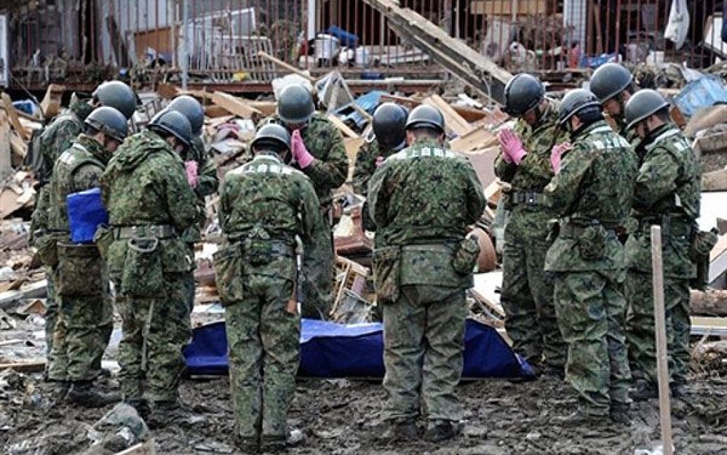 Японія, Мінамісанріку. Японські солдати моляться над тілами загиблих людей, знайдених у смітті після руйнівного цунамі і землетрусу у префектурі Мінамісанріку. Кількість загиблих і зниклих без вісті під час землетрусу і цунамі в Японії перевищила 16000. / © AFP