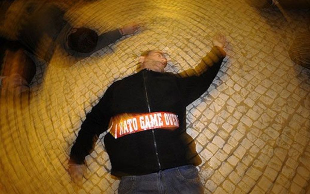 Португалія, Лісабон. Демонстрант лежить на землі під час акції протесту проти НАТО, яку провели в центрі Лісабона, де проходить саміт країн-членів НАТО. / © AFP