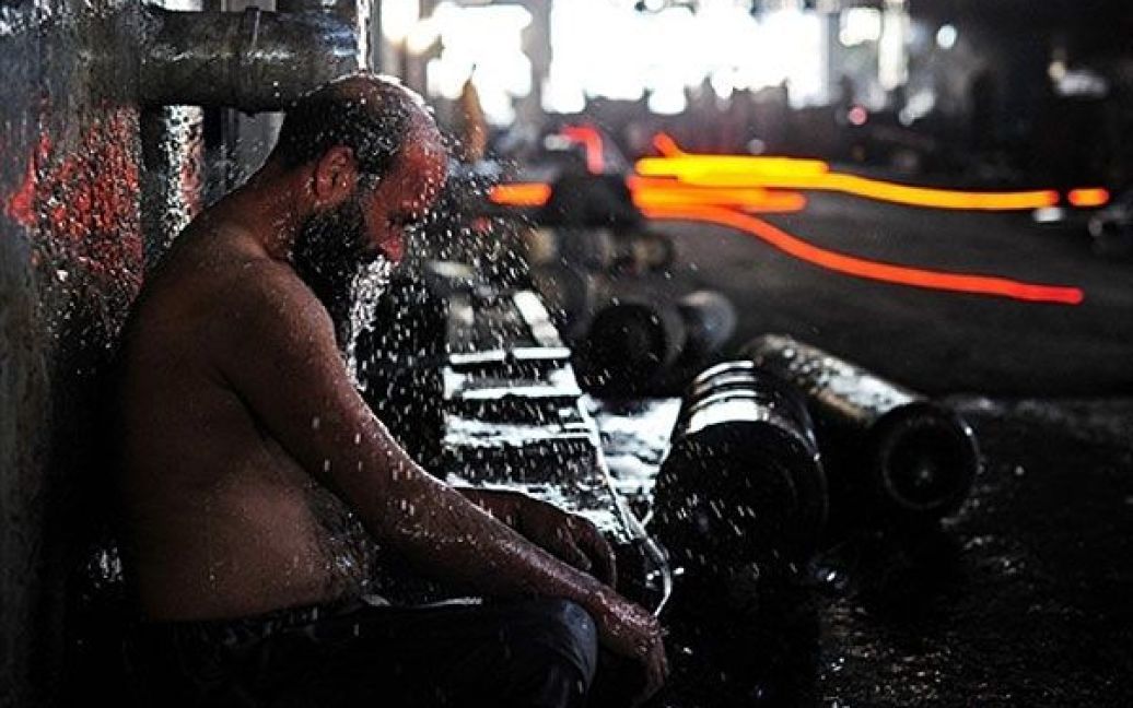 Пакистан, Ісламабад. Сталевар миється після роботи із розплавленою
сталлю на металургійному комбінаті у Ісламабаді. Працівники на цьому
заводі працюють по одній годині на добу через сильну спеку і тому, що
подібна робота вимагає повної концентрації, необхідної для безпеки. / © AFP