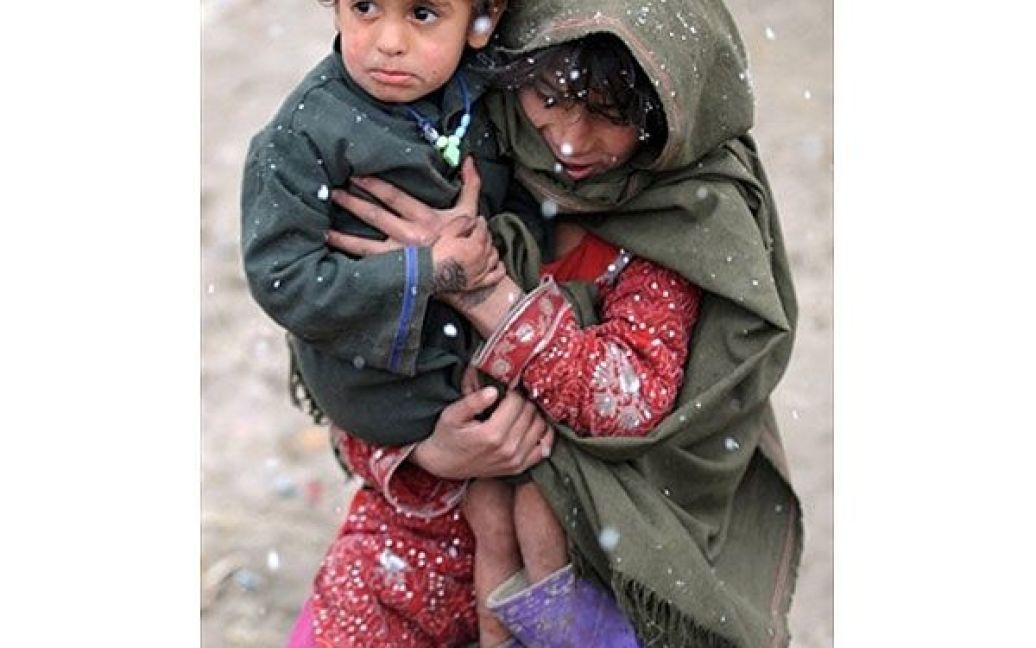Афганістан, Кабул. Афганська дівчинка тримає на руках свого молодшого брата у таборі для вимушених переселенців в Кабулі. Більше  36 тисяч афганців були змушені залишити свої будинки через проведення військових операцій проти талібів на півдні Афганістану. / © AFP