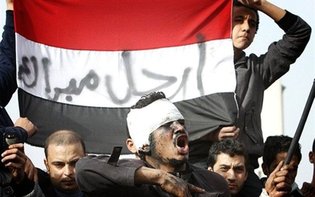 Єгипет, Каїр. Єгипетські демонстранти тримають єгипетський прапор із написом арабською "Мубарак йди!" під час багатотисячної антиурядової демонстрації у Каїрі. / © AFP