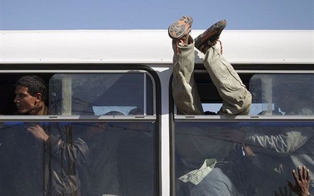 Туніс. Чоловіку допомагають залізти до автобуса через вікно. Майже 10 тисяч осіб втекли з Лівії до табору біженців в Тунісі. / © AFP