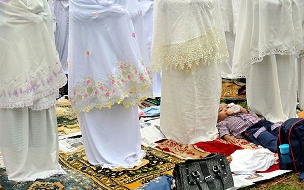 Індонезія, Джакарта. Малюк відпочиває, доки індонезійські жінки-мусульманки здійснюють молитву на свято Іль аль-Адха у Джакарті. Індонезійські мусульмани разом з тисячами інших мусульман у всьому світі святкують свято жертвоприношення, яке знаменує закінчення хаджу. / © AFP