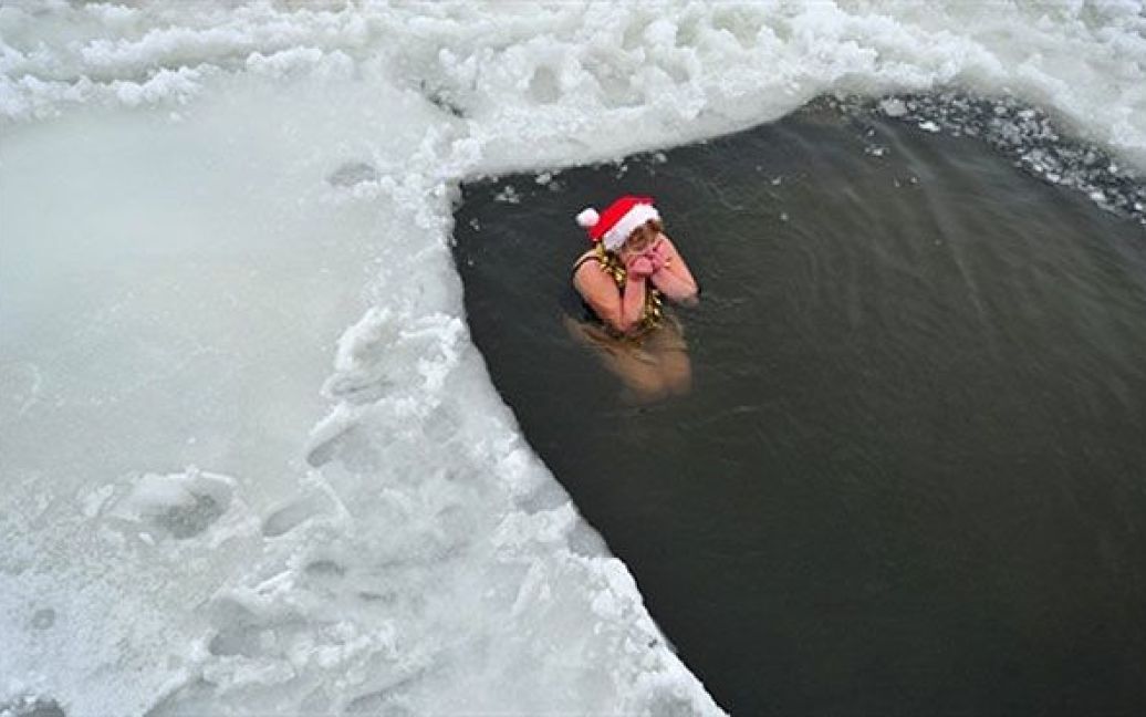 Німеччина, Берлін. Учасниця берлінського клубу плавців "Berliner Seehunde" занурюється у озеро Оранке під час традиційного різдвяного купання у Берліні. / © AFP