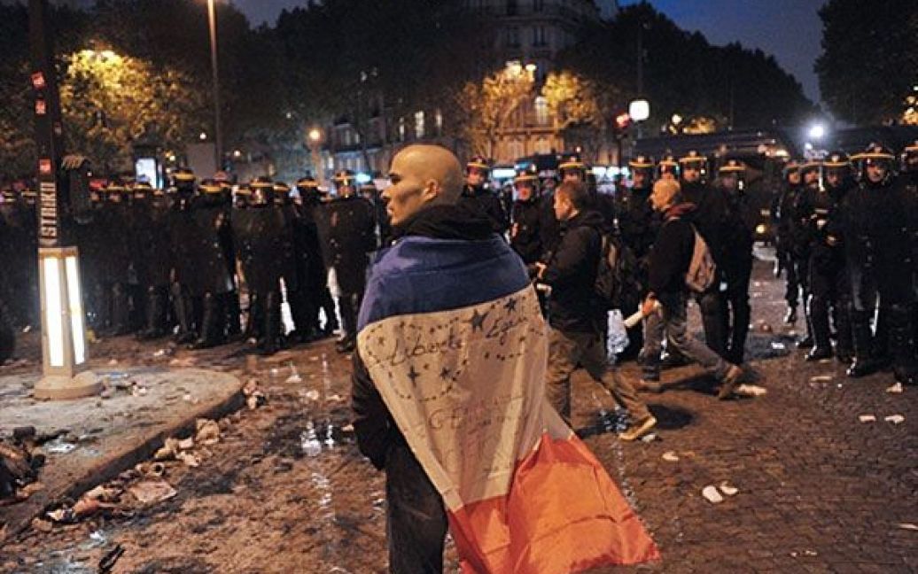 Франція, Париж. Чоловік стоїть перед поліцейськими під час демонстрації у Парижі, де протягом 9 днів проходили щоденні акції протесту проти урядової пенсійної реформи, який був офіційно прийнятий законодавцями / © AFP