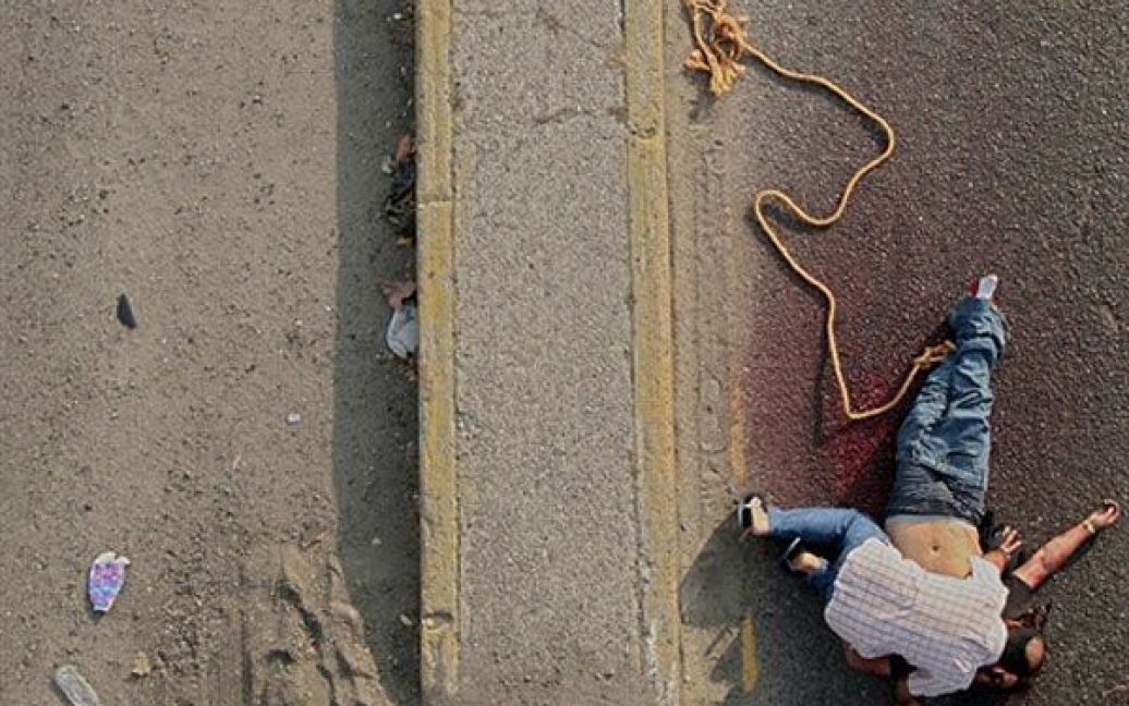 Мексика, Акапулько. Людина тужить над тілом родича, який став однією з трьох жертв нарковійн, знайдених обезголовленими і частково розчленованими на дорозі в районі Ла-Сіма, Акапулько. / © AFP