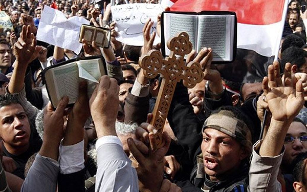 Єгипет, Каїр. Єгипетські християни-копти і мусульмани тримають хрест і священну книгу мусульман Корану під час акції протесту на площі Тахрір у центрі Каїра. / © AFP