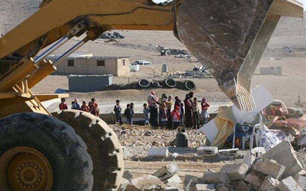 Палестинські бедуїни дивляться, як ізраїльський військовий бульдозер руйнує їхні будівлі у таборі поблизу села Дакека, де мешкали близько 300 бедуїнів. / © AFP