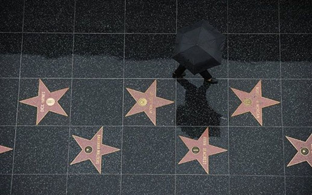США, Голлівуд. Турист йде під дощем голлівудською Алеєю слави. У Лос-Анджелесі менше ніж за тиждень випала третина середньорічної кількості опадів. / © AFP