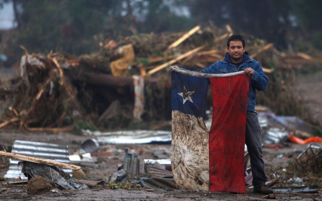 Чоловік з чилійським прапором після землетрусу у місті Пеллуху у лютому. (AP Photo / Roberto Candia) / © The Boston Globe