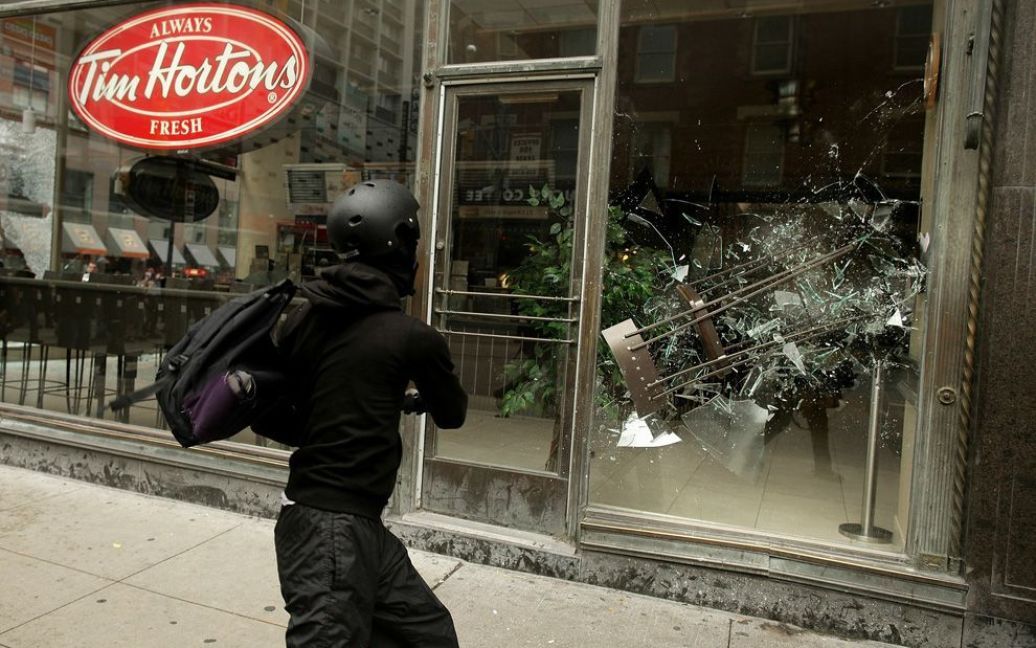 Демонстрант-антиглобаліст, прихильник "Чорного блоку", кидає стілець у вікно кафе Tim Horton&#039;s під час акцій протесту проти саміту G-20 в Торонто. (Simon Hayter / Getty Images) / © The Boston Globe