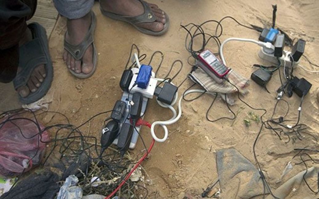Туніс, Чоуча. Біженці з Лівії заряджають свої мобільні телефони у таборі біженців на неподалік від кордону з Лівією. Туніські військові та ООН повідомила, що у таборі мешкають 16 тисяч осіб, більшість з яких немає коштів на власне житло. / © AFP
