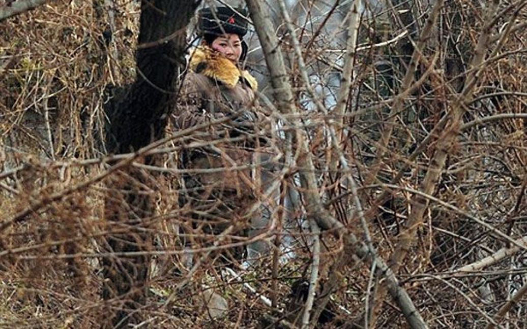 Китай, Даньдун. Озброєна північнокорейська жінка-військовий патрулює берег річки Ялу. / © AFP