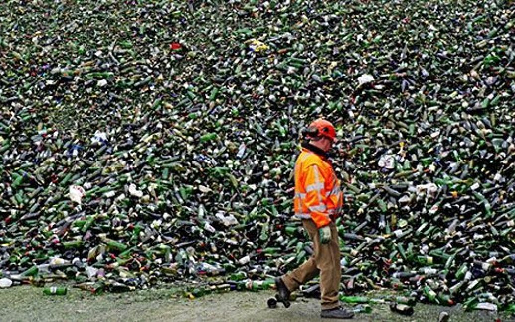 Нідерланди, Хейнінген. Працівник заводу з переробки скла у Хейнінгені проходить повз гору скляних пляшок. / © AFP