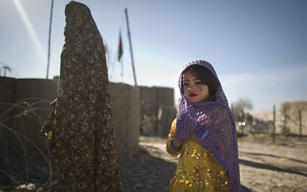 Афганістан, Муса-Кала. Афганська дівчинка та її матір гуляють поруч із базою Муса-Кала, провінція Гільменд. Афганістан страждає від низького рівня освіти, особливо серед дівчаток, низького рівня грамотності тощо. Країна також має другий у світі найгірший показник зі смертності немовлят. / © AFP