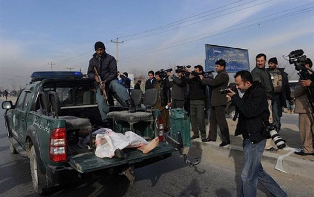 Афганістан, Кабул. Журналісти фотографують одного зі смертників, який лежить у багажнику поліцейського автомобіля поблизу із місцем теракту в Кабулі. Два терористи-смертники здійснили напад на автобус з афганськими військовими, в результаті якого загинули п&#039;ятеро військовослужбовців, ще дев&#039;ять отримали поранення. / © AFP