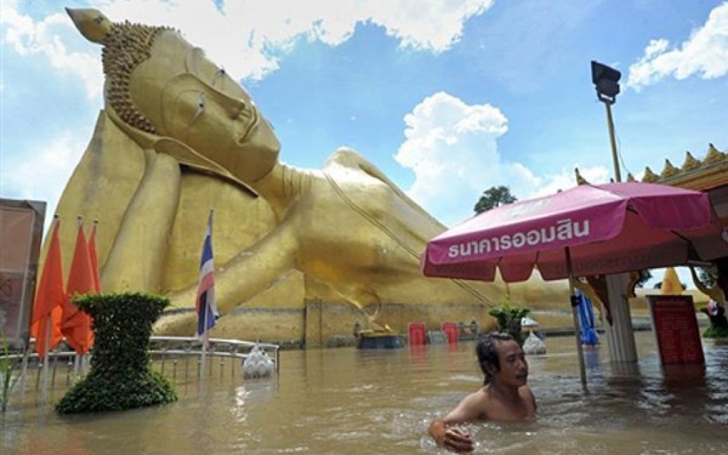 Чоловік пливе крізь затоплену центральну площу Аюттхаї. Таїланд вже 2 тижні страждає від повені, викликаної зливами. Кілька мільйонів таїландців втратили свої домівки, переважна кількість сільськогосподарських угідь у північних провінціях повністю знищено. / © AFP