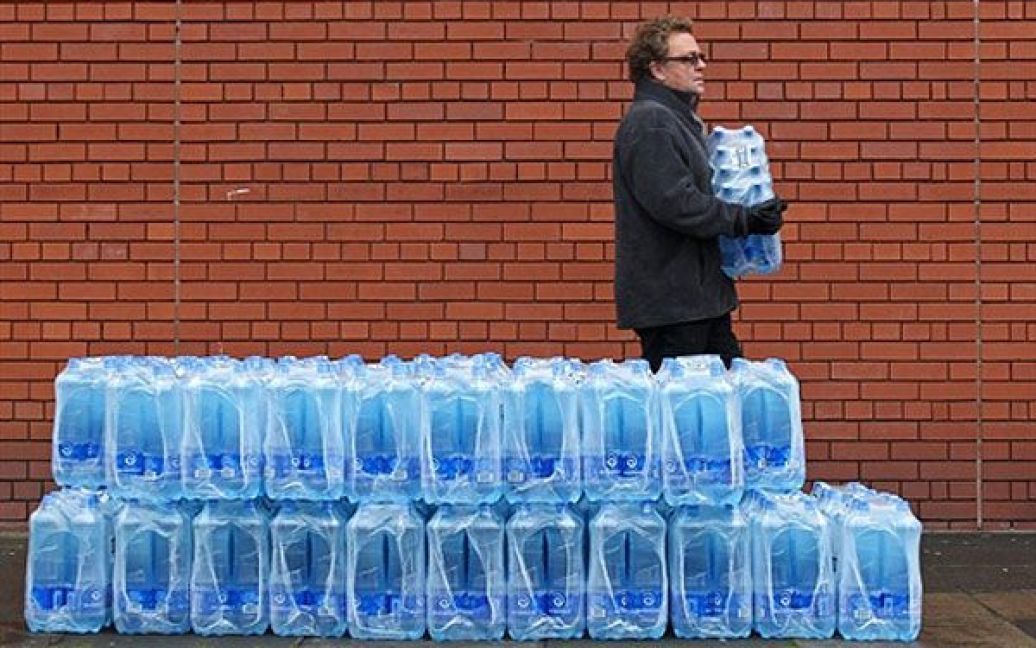 Великобританія, Белфаст. Чоловік забирає воду у пляшках, яку безкоштовно розповсюджує міська рада перед центром Олімпія у Белфасті, Північна Ірландія. Через комунальну аварію майже сорок тисяч людей залишилися без води і каналізації. Водопровідні труби луснули під час сильних морозів, десятки тисяч людей залишились без води більше ніж на тиждень. / © AFP