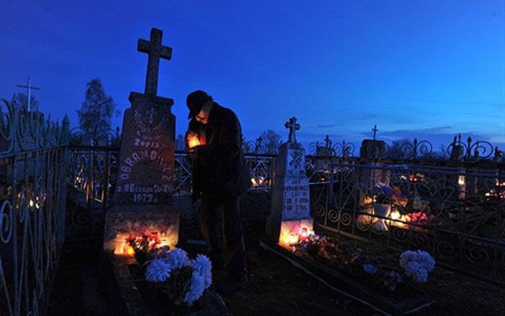 Білорусь, Борунов. Чоловік ставить свічки на могилу на цвинтарі біля білоруського села Борунов на честь свята Дзяди (Дня пам&#039;яті). / © AFP