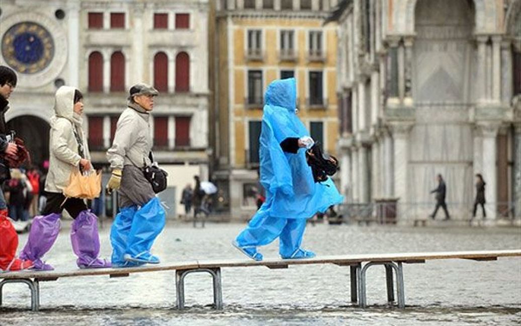 Італія, Венеція. Туристи переходять по дошках затоплену площу Святого Марка у Венеції. "Висока вода", яка поєднуэ високі припливи і сильний вітер у Адріатичному морі, встановилась у Венеції на рівні 111 см. / © AFP