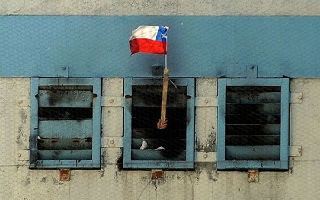 Чилі, Сантьяго. Ув&#039;язнений розмахує чилійським прапором зі своєї камери у в&#039;язниці Сан-Мігель. В результаті пожежі, яка спалахнула у в&rsquo;язниці, загинули більше 80 ув&#039;язнених. / © AFP