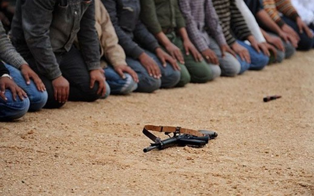 Лівійська Арабська Джамахірія. Лівійські бойовики моляться перед боєм з силами Муаммара Каддафі поблизу міста Рас Лануф. / © AFP