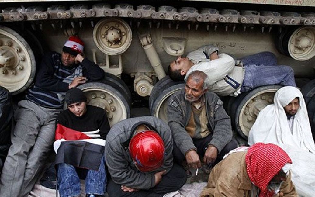 Єгипет, Каїр. Єгипетські антиурядові демонстранти сидять поруч із військовою машиною на площі Тахрір в центрі Каїра. У Єгипті тривають протести із закликами до повалення президента Хосні Мубарака. / © AFP