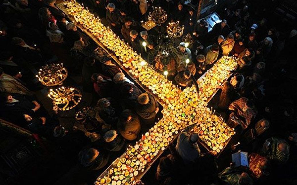 Болгарія, Благоєвград. Люди збираються навколо хреста, викладеного запаленими свічками на банках з медом, у церкві Пресвятої Діви у Благоєвграді під час святкування Дня святого Харлампія, захисника бджолярів. / © AFP