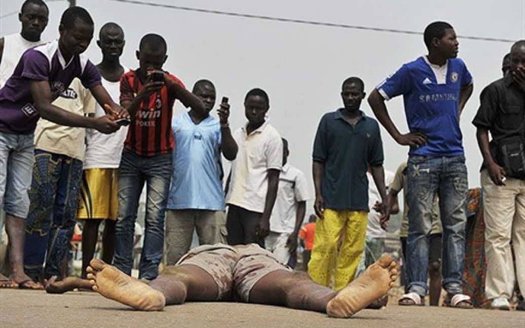 Кот-д&#039;Івуар, Абіджан. Мешканці фотографують мобільними телефонами тіло людини, вбитої під час стрілянини у Абіджані. Принаймні, двоє цивільних осіб були вбиті під час перестрілок у столиці Кот-д&#039;Івуара. / © AFP