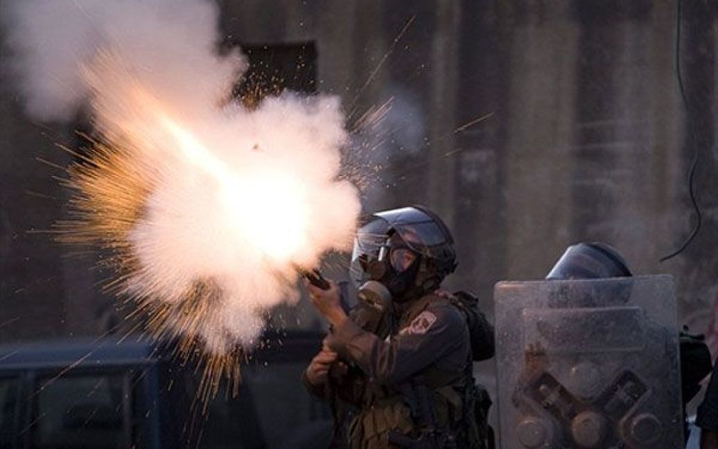 Єрусалим. Ізраїльський прикордонник стріляє гранатою зі сльозоточивим газом у палестинських демонстрантів, які кидають у військових каміння, під час зіткнень у таборі біженців на околиці Єрусалиму. / © AFP