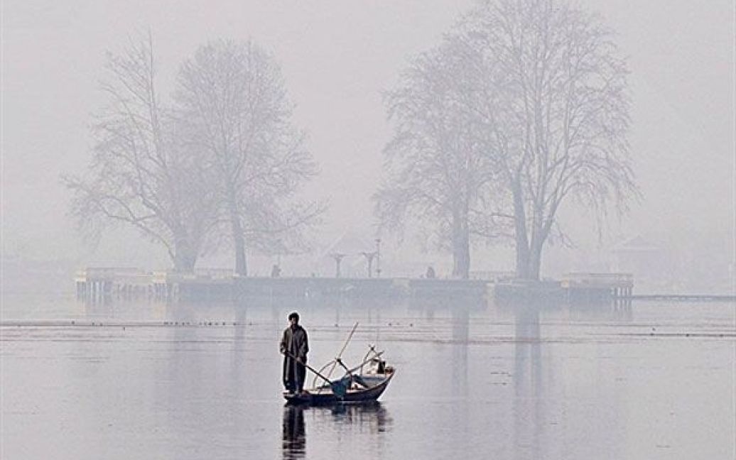 Індія, Срінагар. Чоловік стоїть у своєму човні на озері Дав у холодний і туманний день у Срінагарі. / © AFP