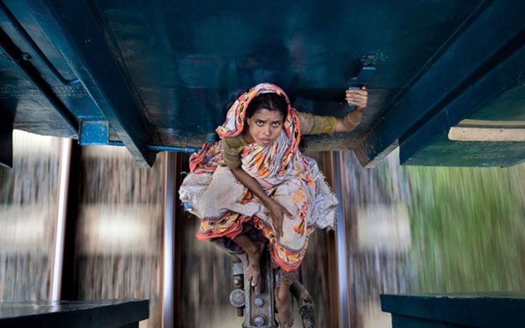Небезпечна подорож. Жінка їде між вагонів місцевого поїзду на північ від Дакки, столиці Бангладеш. Фото Емі Елен Йоханссон. / © National Geographic