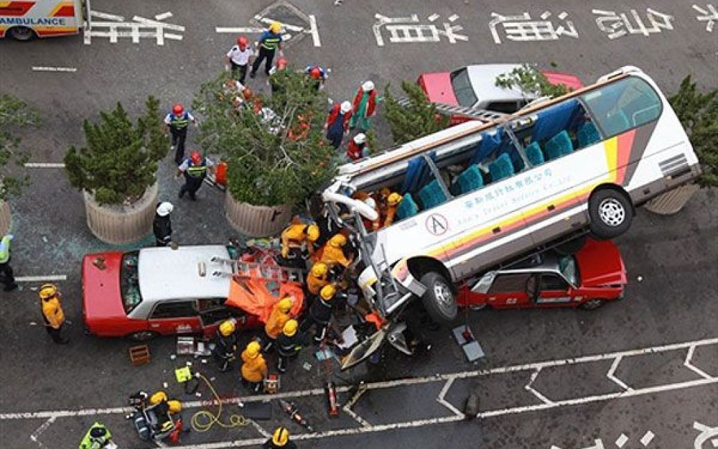 Китай, Гонконг. Пожежні зібралися навколо автобуса, який звалився з естакади неподалік від міжнародного аеропорту Гонконгу. Автобус їхав по естакаді, потім злетів з неї і приземлився на дахи двох таксі, поранивши двох осіб. / © AFP