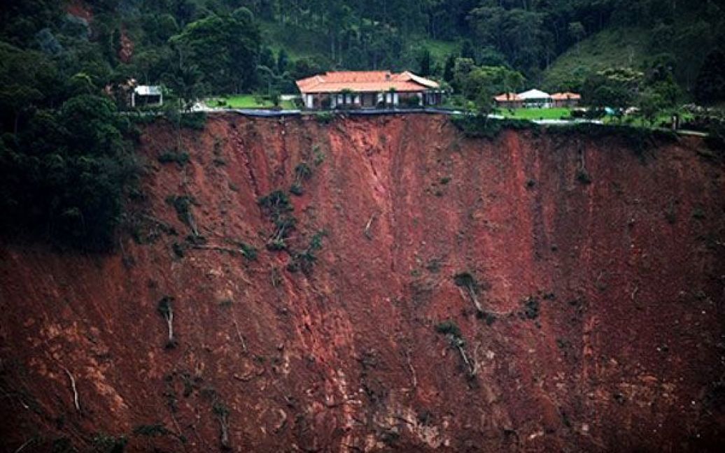 Бразилія, Поко Фундо. Будинок стоїть на краю урвища, що утворилось в результаті зсуву у місцевості Поко Фундо, штат Ріо-де-Жанейро. В результаті найбільш руйнівних зсувів в історії Бразилії, загинули майже 700 осіб. / © AFP