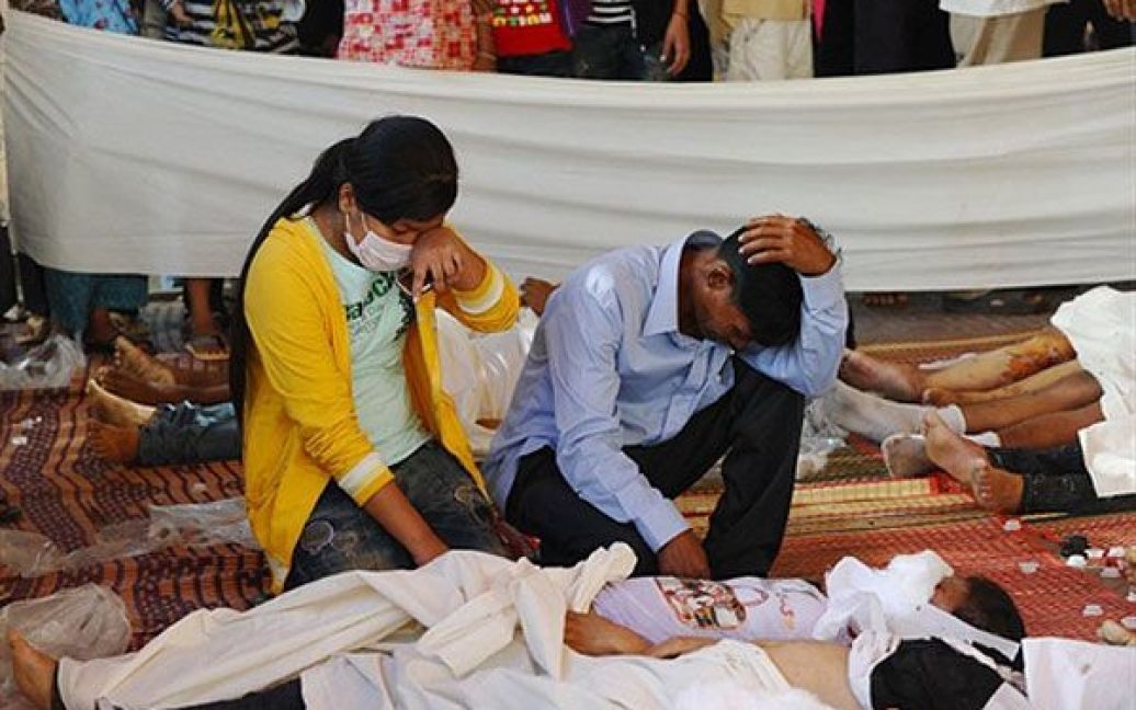 Камбоджа, Пномпень. Люди сумують, сидячи поруч із тілом свого молодшого брата, який загинув під час трагедії, що сталась у Пномпені під час святкування фестивалю води. Більше 350 людей загинули, сотні людей отримали травми у тисняві, яка виникла на вузькому мосту, де зібрались тисячі людей. / © AFP