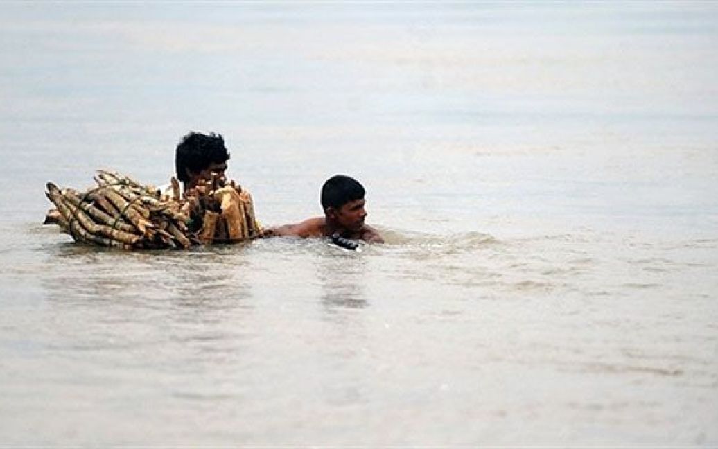 Шрі-Ланка, Баттікалоа. Шрі-ланкійці, які постраждали від повеней, пробираються крізь затоплену вулицю в місті Баттікалоа. Щонайменше 21 людина загинула, більше 1,2 млн. постраждали від мусонних злив, які затопили більшу частину острова. / © AFP
