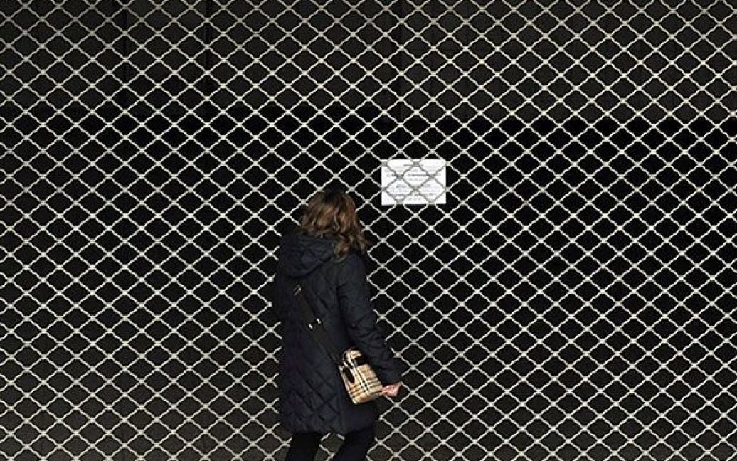 Греція, Афіни. Жінка читає знак, вивішений перед закритим входом до станції метро в Афінах, де відбувся черговий 24-годинний страйк працівників громадського транспорту. Рух у грецькій столиці було паралізовано. / © AFP