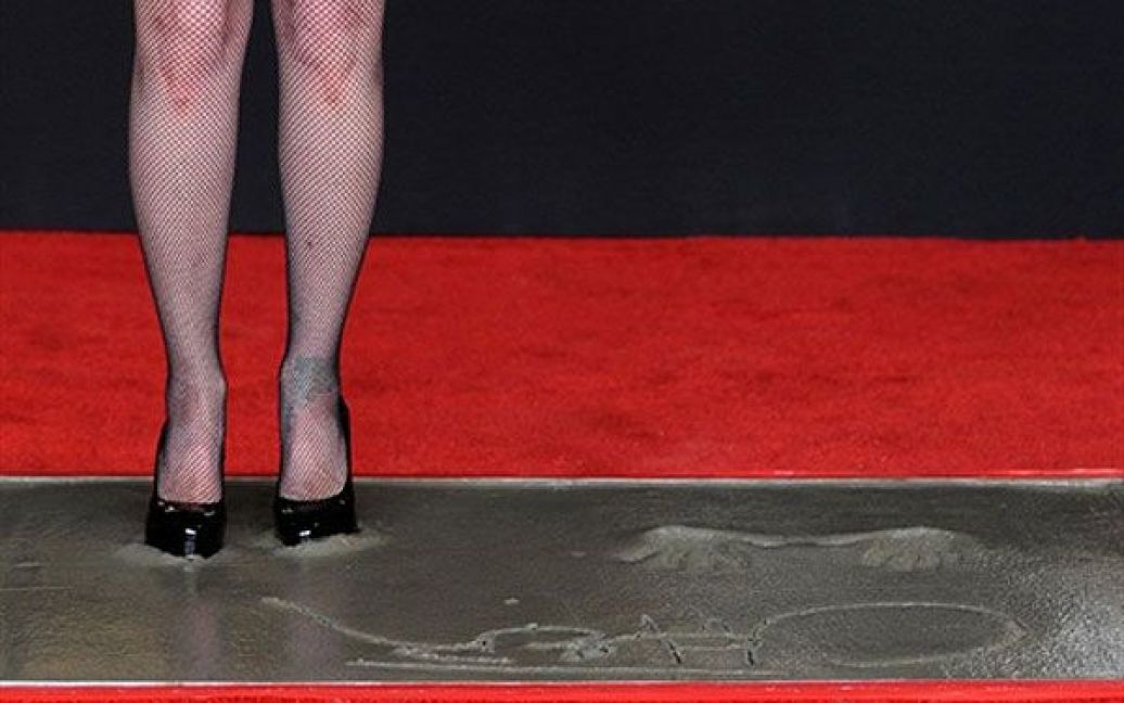 США, Голлівуд. Співачка і актриса Шер стоїть у вологому цементі під час церемонії, коли відбитки її руки та слід були увічнені перед театром Grauman&#039;s у Голлівуді. / © AFP