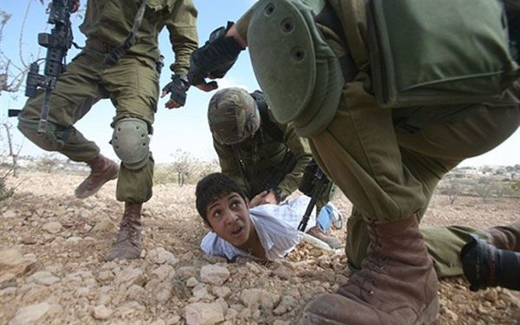 Хеврон. Палестинського юнака затримують ізраїльські солдати за кидання каміння під час акції протесту іноземних, ізраїльських і палестинських демонстрантів проти єврейського поселення поблизу Кармі Цур. / © AFP