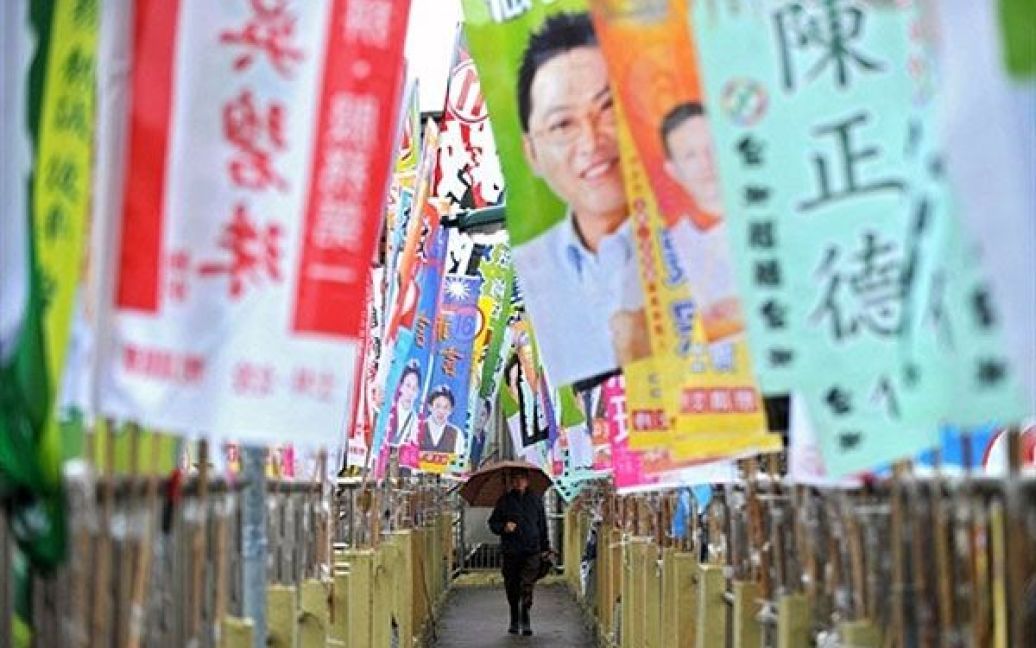 Тайвань, Тайпей. Чоловік йде вулицею, на якій розвішені плакати
передвиборчої кампанії. Виборці у п&#039;яти містах Тайваню взяли участь у
виборах мерів, які розглядають, як ключовий показник уподобань
виборців напередодні президентських виборів 2012 року. / © AFP