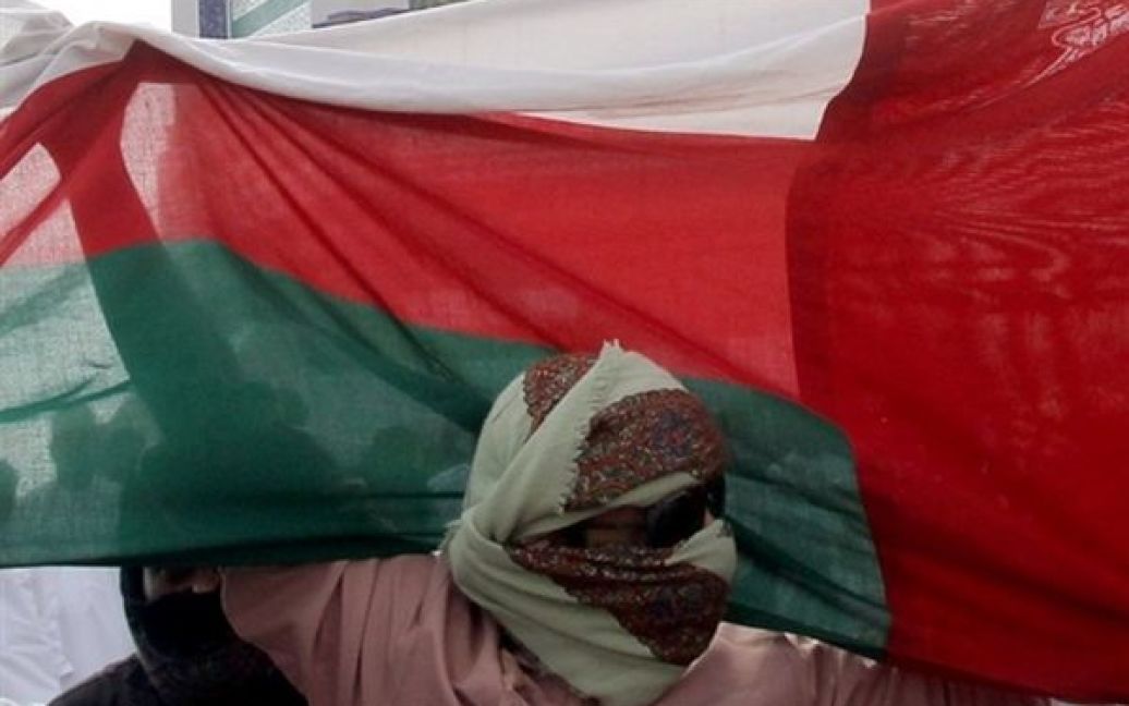 Оман, Сохар. Оманський протестувальник у масці тримає національний прапор під час демонстрації,  учасники якої вимагали отримання роботи і проведення реформ у країні. / © AFP