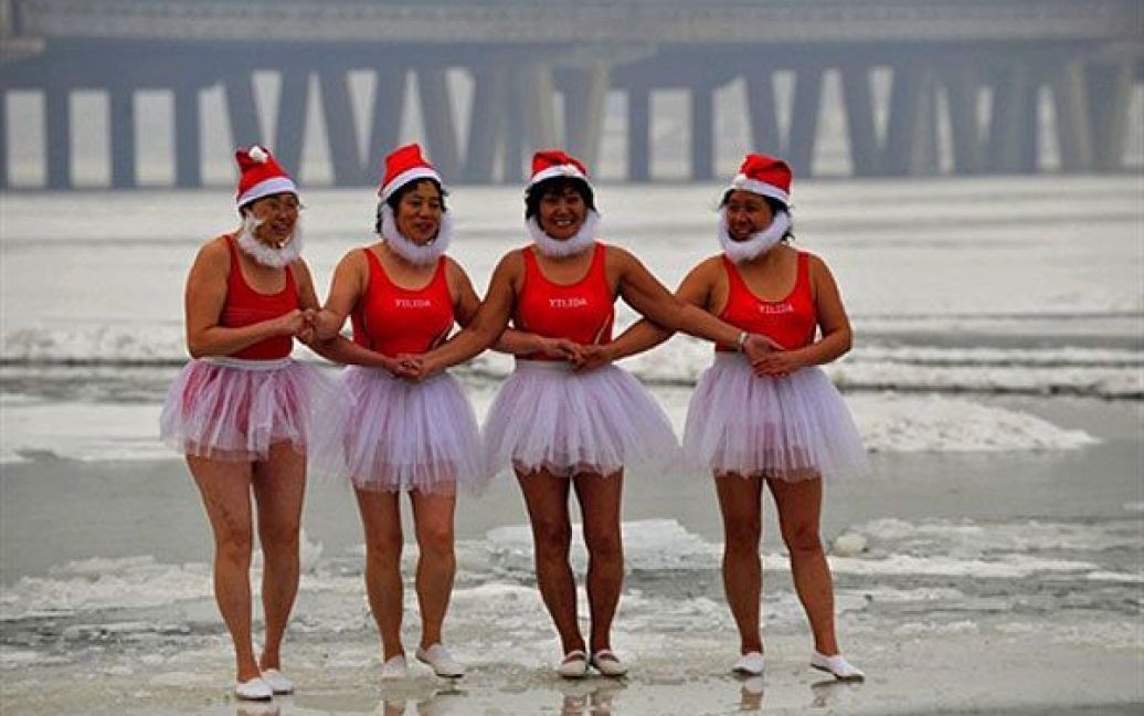 Китай, Шеньян. Група літніх китайських жінок у костюмах "сантарін" стоять на льоду перед тим, як зануритися у крижану воду. Зимове плавання є популярним серед літніх осіб. Вважається, що це поліпшує кровообіг, знімає стрес, позбавляє болів, збільшує життєву силу. / © AFP
