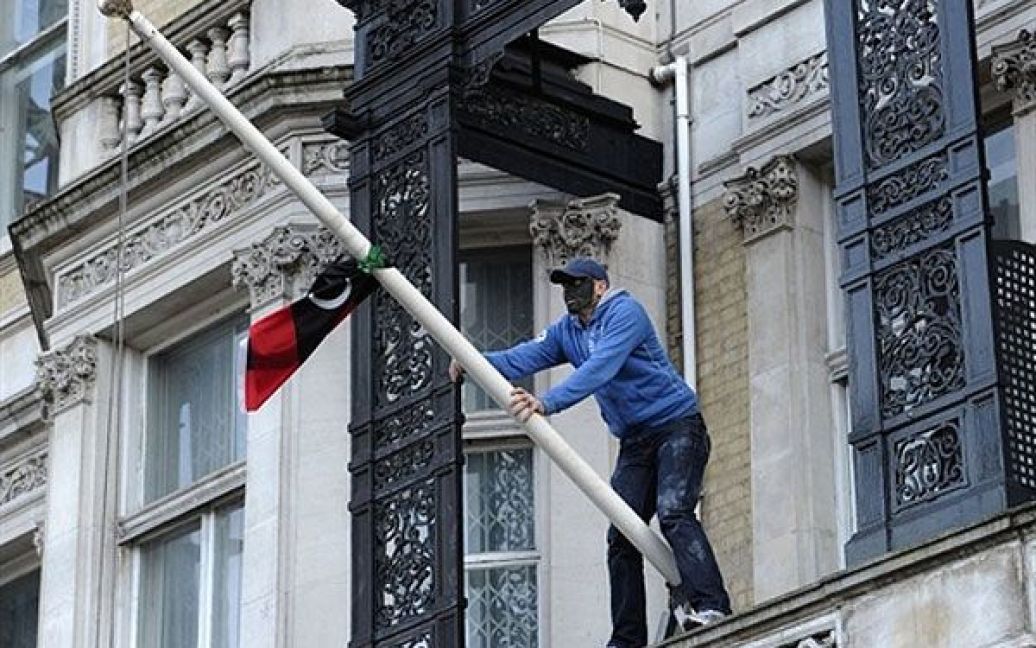 Великобританія, Лондон. Демонстрант розвішує лівійський прапор на балконі лівійського посольства в центрі Лондона. / © AFP